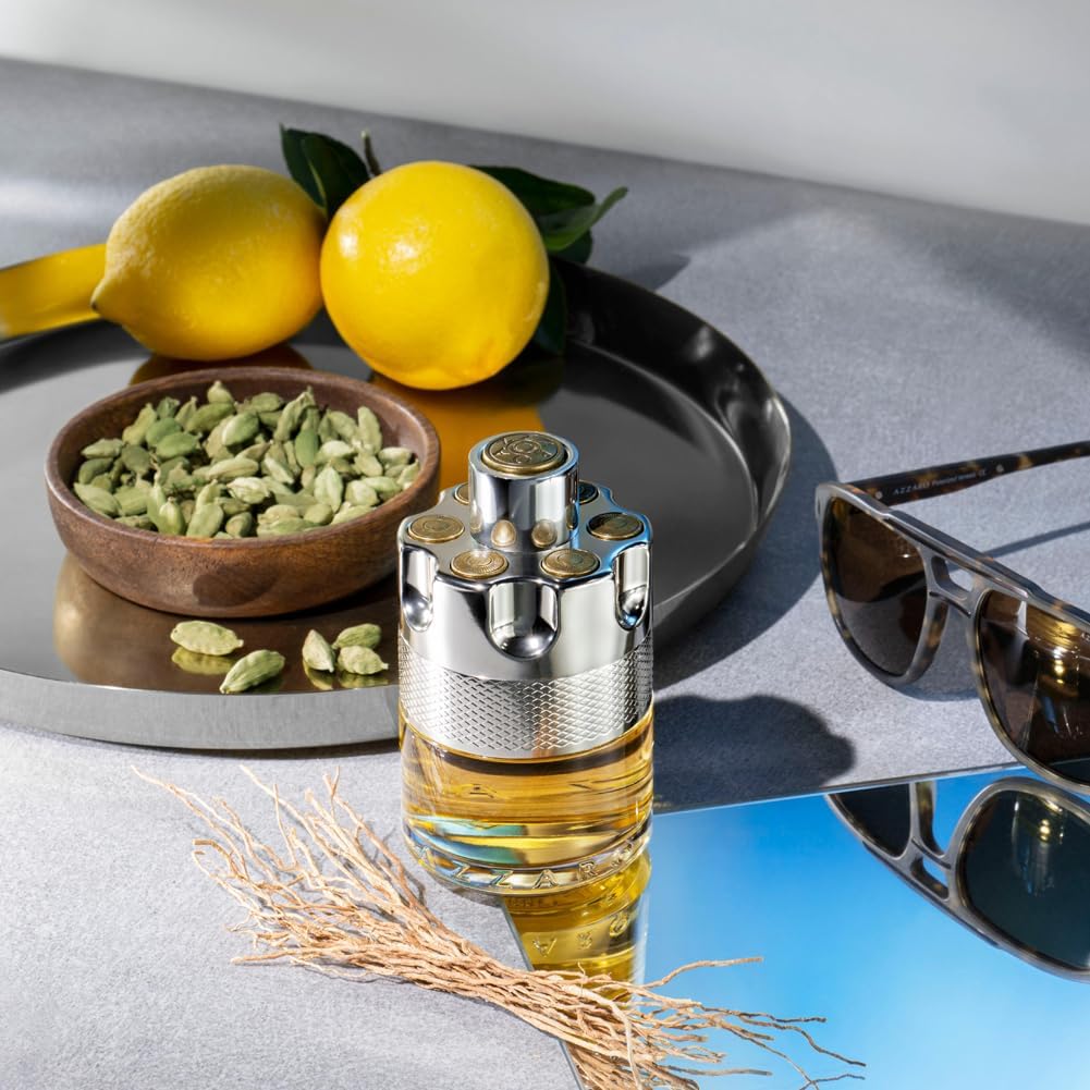 Perfume bottle with lemons, green leaves, and sunglasses on a reflective surface